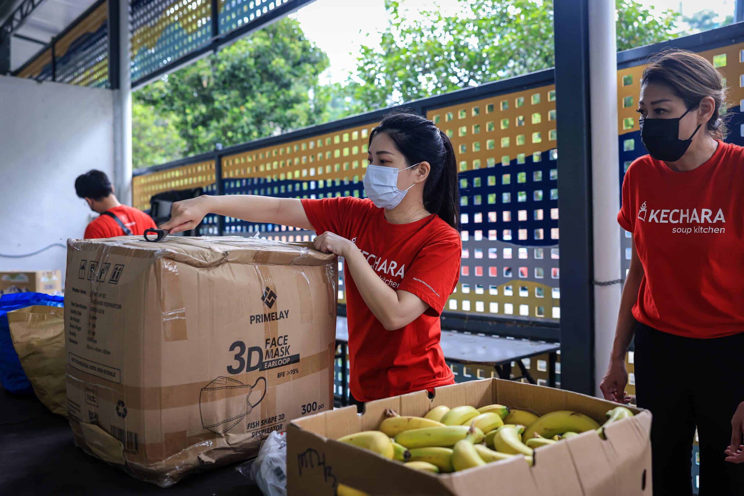 Food bank staff member unboxing face masks.