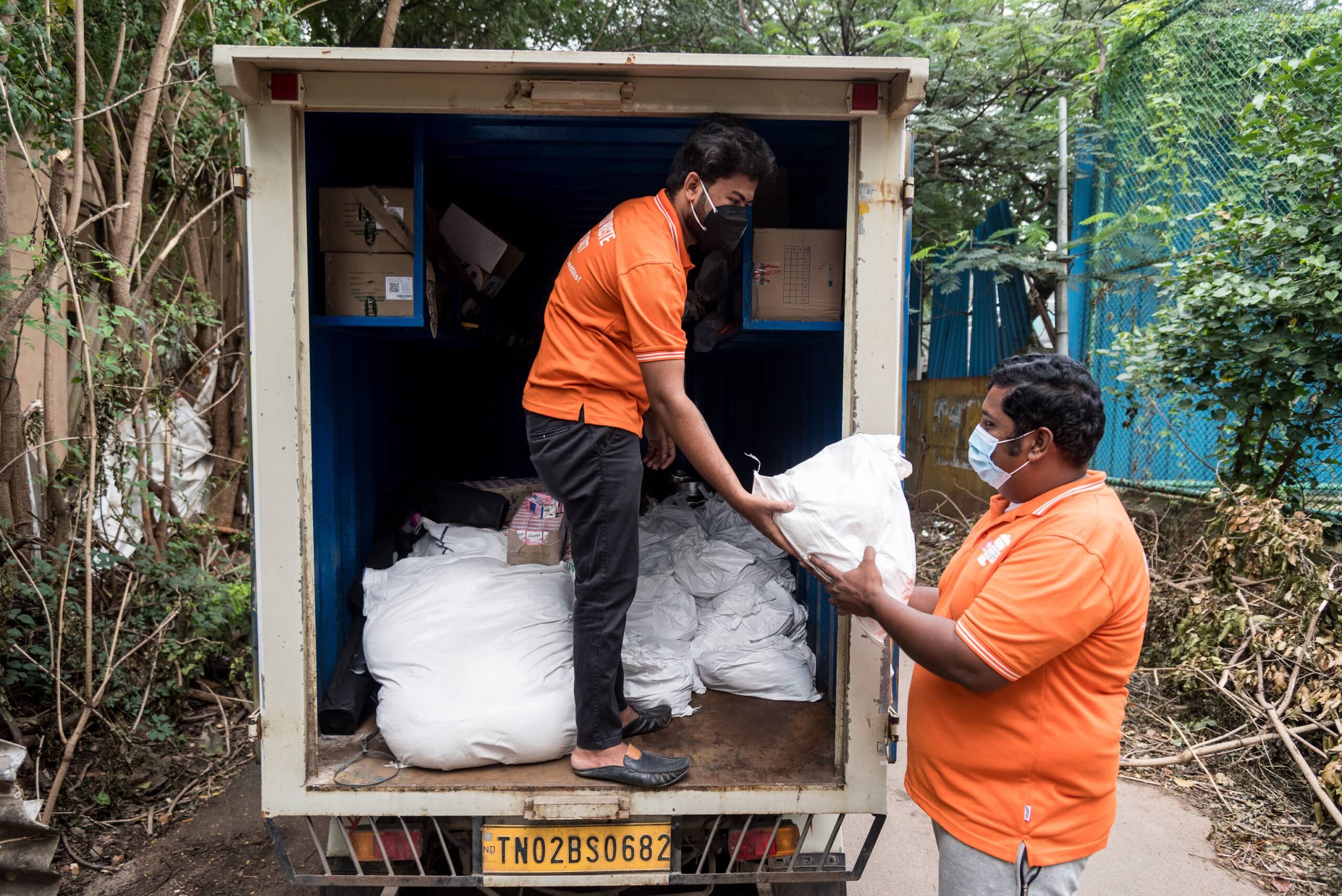 Volunteers in personal protective equipment unload fresh produce from a large truck.