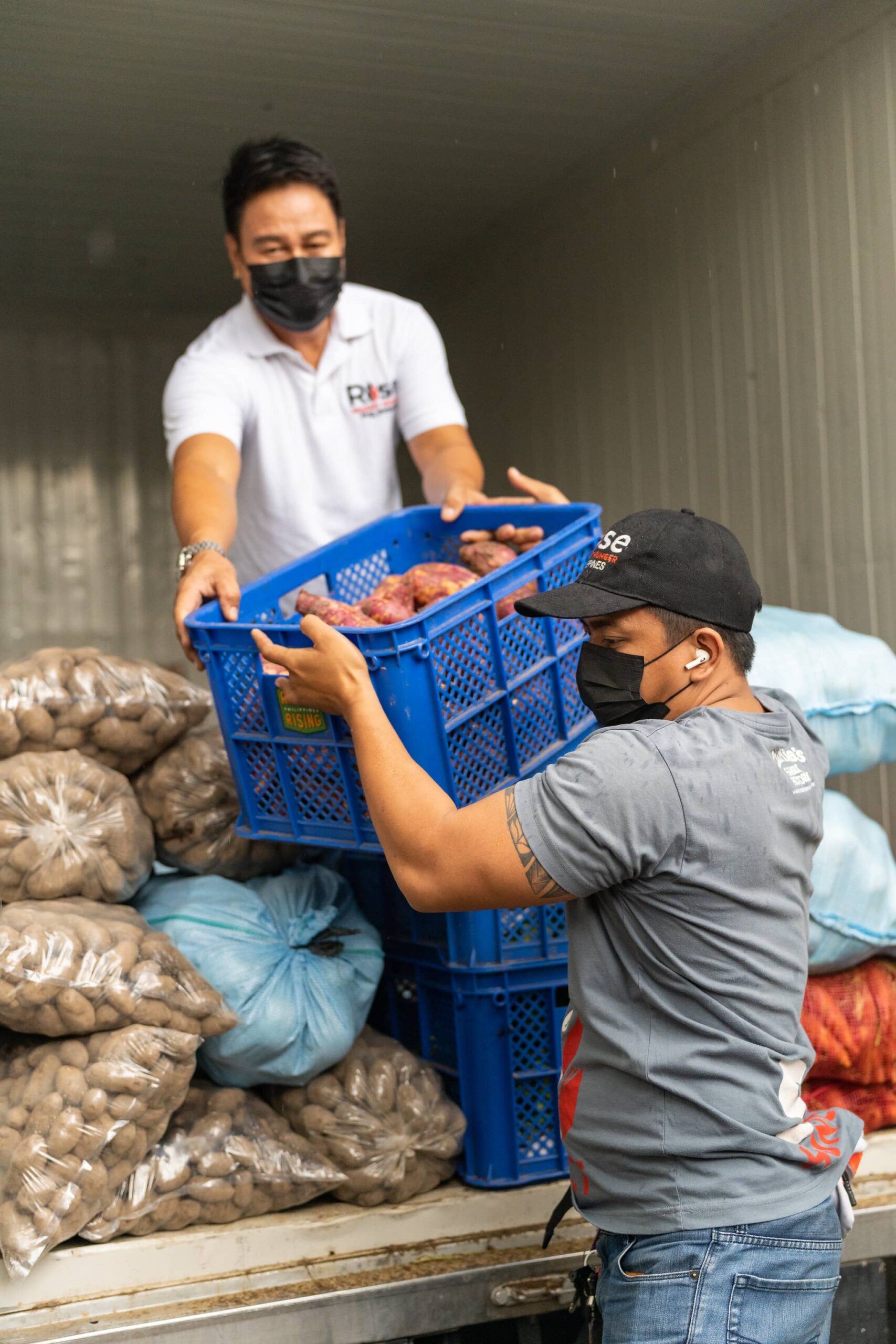 A food bank staff members helps carry crates of donated produce.